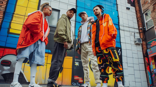 Guide to Men's Streetwear 2025 Feaatured Image - Some Mens in Streetwear Clothes in a ally with graffiti on the wall
