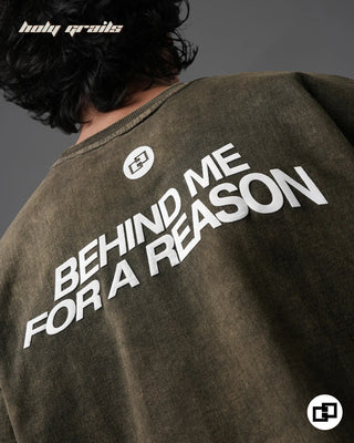 Person wearing 'Behind For A Reason' Olive Green 240 GSM 100% Cotton Oversized Acid Wash T-Shirt with text on the back, brand logo visible - Back Close Up