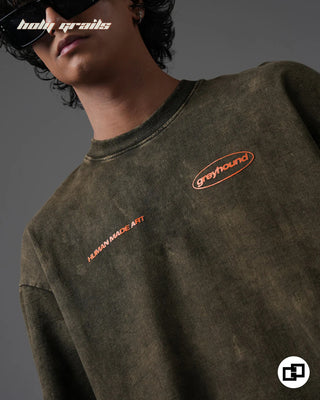 Person wearing 'Behind For A Reason' Olive Green 240 GSM 100% Cotton Oversized Acid Wash T-Shirt with 'human made art' and 'greyhound' logos on a gray background - Front Close Up
