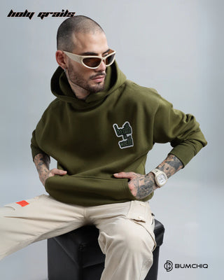 Guy Sitting on a Stool in Streetwear 'Money' Green Olive 350-370 GSM 100% Cotton DTF Print Oversize Hoodie HG x Bumchiq - Front