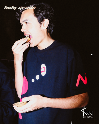 Guy in Streetwear Style 'Bred Format' Black Oversized 260 GSM French Terry Cotton T-Shirt - Side while eating