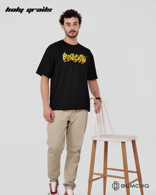 Guy in Streetwear Style 'Simpson' Black 240 GSM French Terry Cotton T-Shirt - Front Hand on Chair