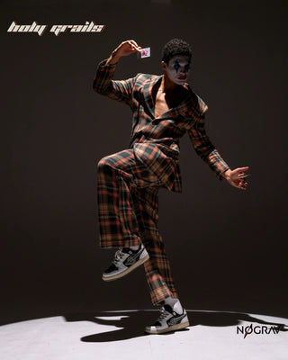 Men in Suit with Joker Makeup wearing Homegrown 'Joker' Premium Black & White PU Upper, Cushioned Footbed, Eva Midsole & Rubber Outsole Lightweight Sneaker HG x NoGrav - Sides, Posing Lifting one leg