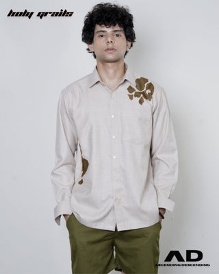 Man wearing a beige shirt with brown floral patterns on a white background