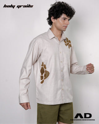 Man wearing a beige full sleeve shirt with brown abstract designs and green shorts